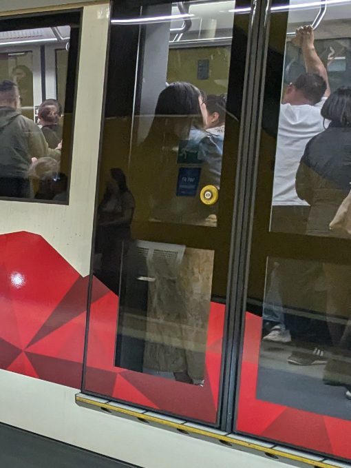 Un botón amarillo brillante en una puerta de cristal transparente de un vagón de tren