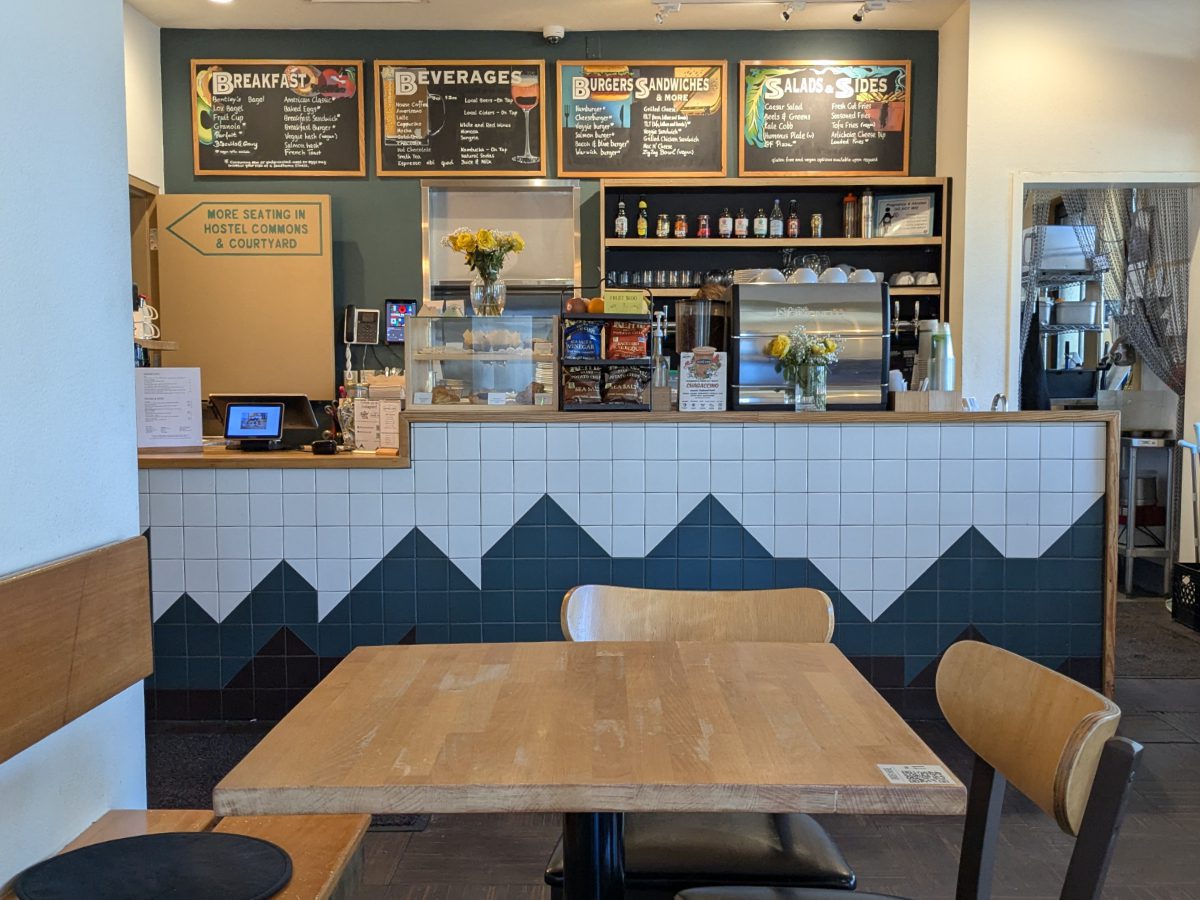 A table at the NW Portland Hostel Cafe with chalkboard menu in background