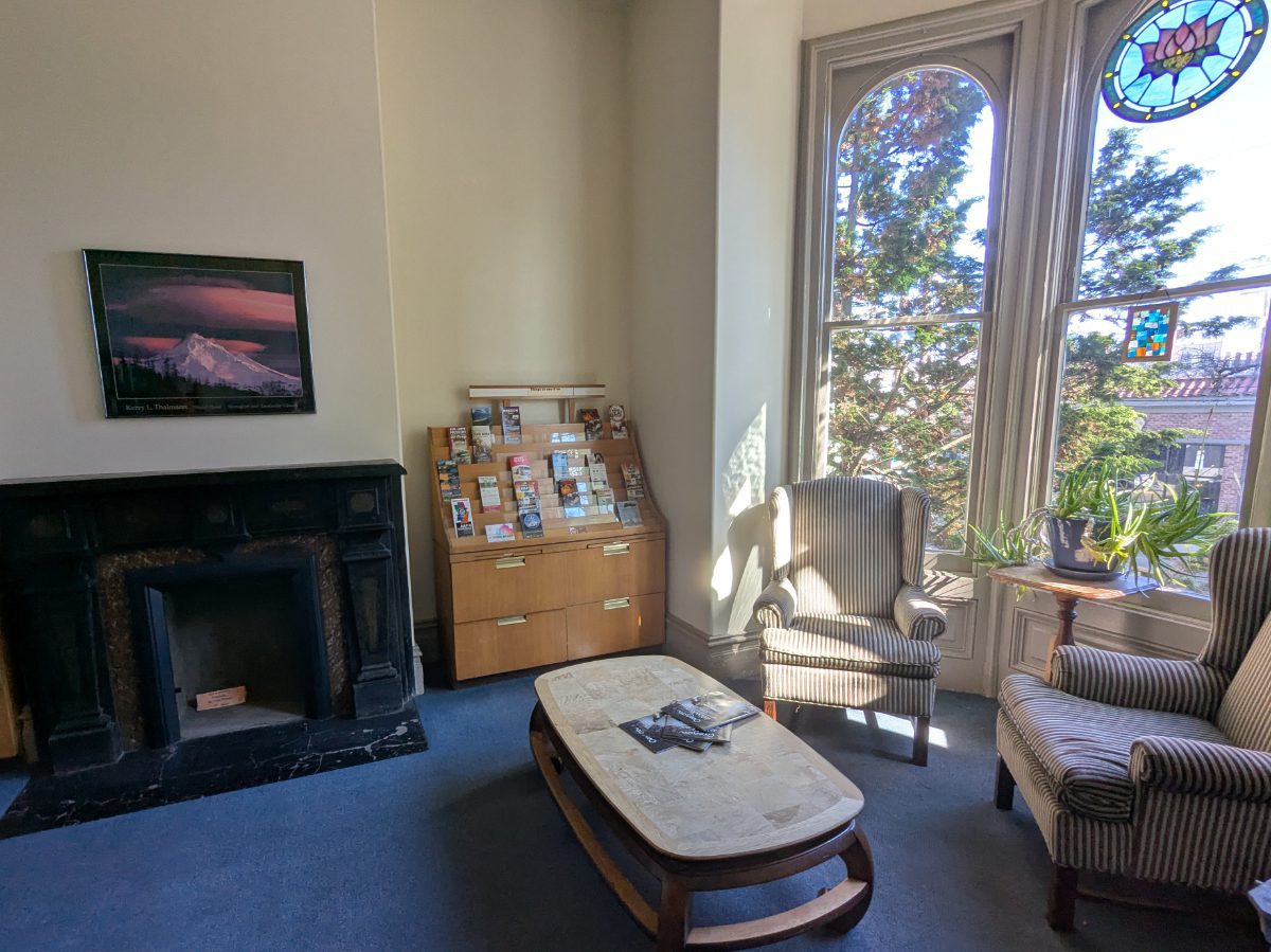 Cozy chairs next to big picture windows and a fireplace at the NW Portland Hostel.