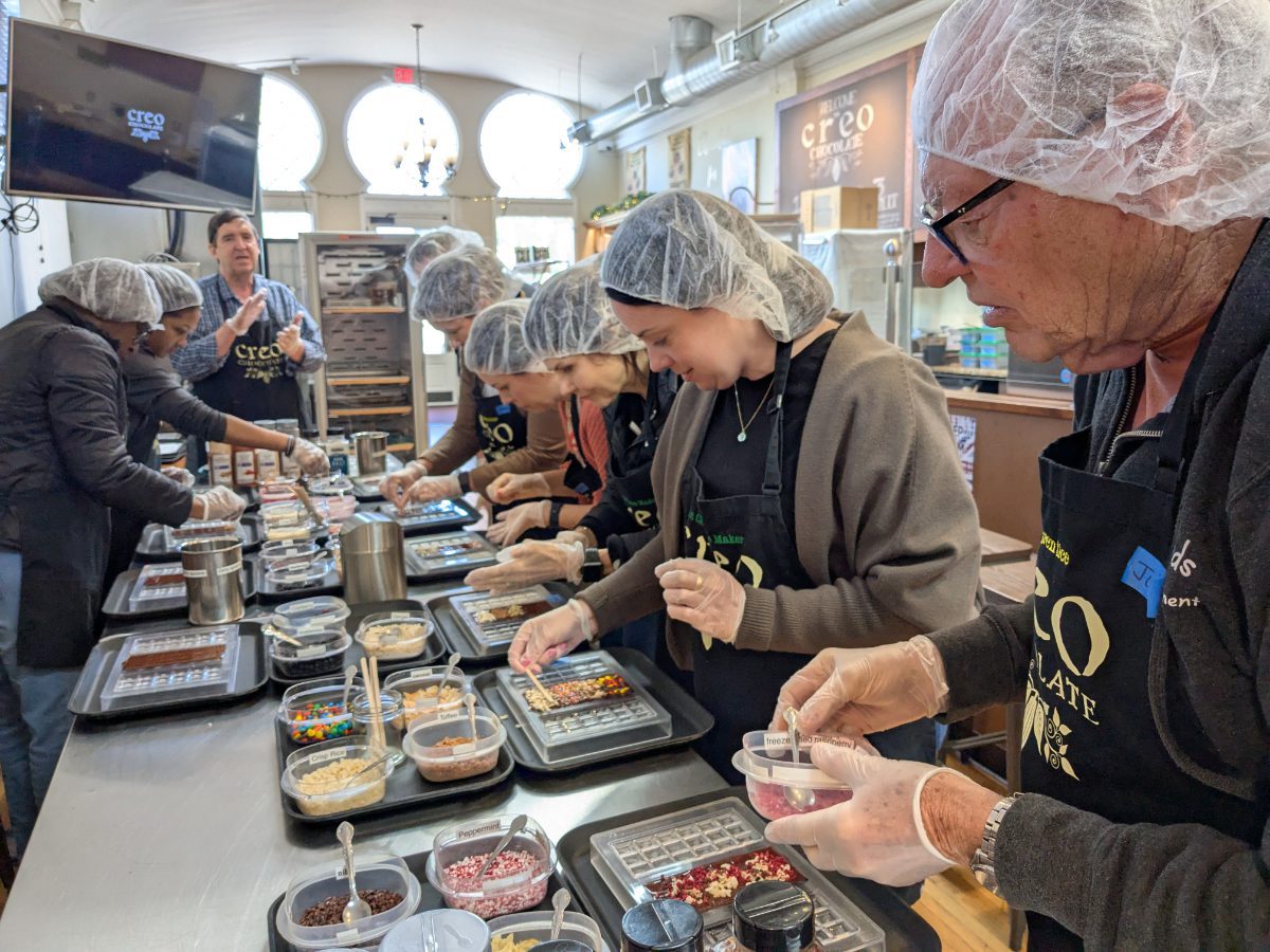Una clase de aprendices de chocolatero trabajando duro para añadir ingredientes al chocolate líquido.