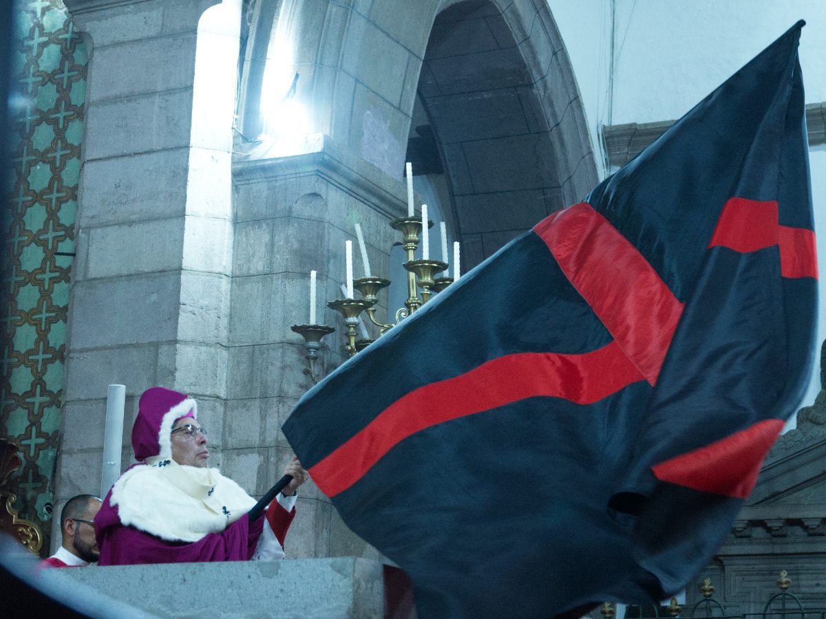 The archbishop waves the immense black flag with red cross over the altar at the Arrastre de Caudas in Quito