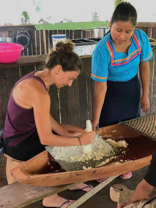  A guest learns how to grate manioc while a Kichwa host looks on