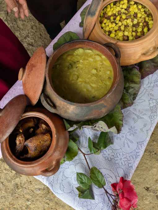 Three clay pots, the first with roasted guinea pig, the second a pottage of vegetables, the third peeled mote with beans.