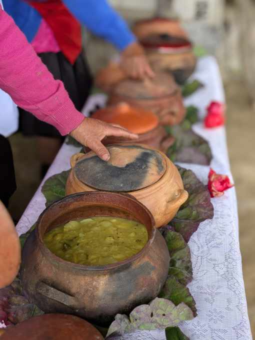 A line of clay pots, the first open with a soup inside, the next with a hand waiting to lift its lid, the others covered.
