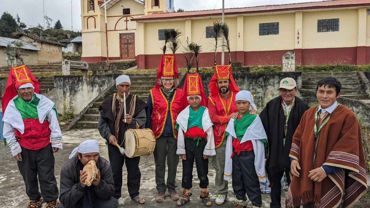 Dancers of Cuemal, the musicians, the hosts, and two tourists pose for a group photo.