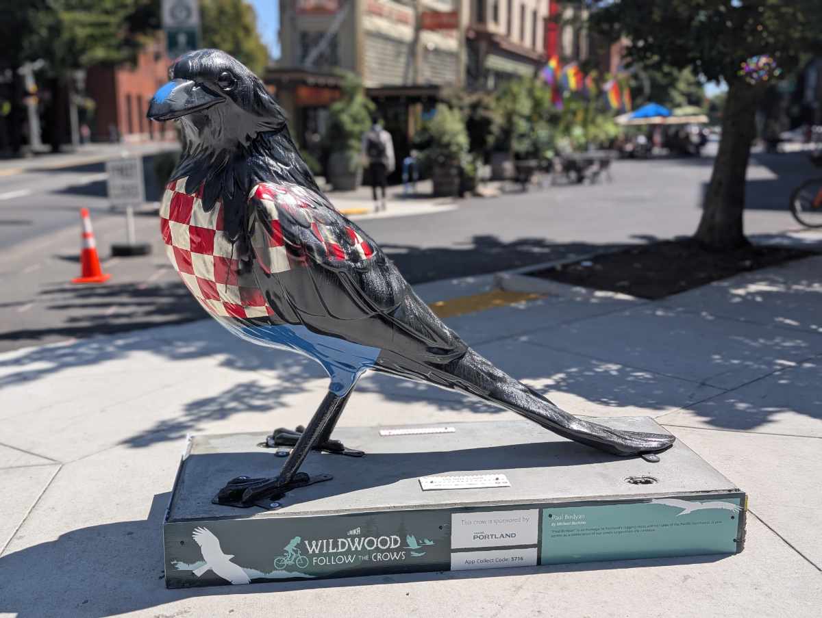 A Paul Bunyan inspired crow, painted black but wearing red and white checkes and blue pants. 
